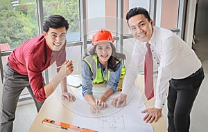 Construction workers , a female architect and two male engineers discussing about the project at office table indoor,smiling and
