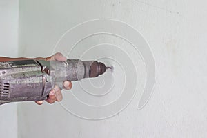 Construction workers and handymen work using an electric drill to drill holes to the wall.