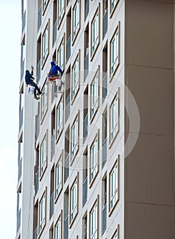 Construction workers hanging on a rope.