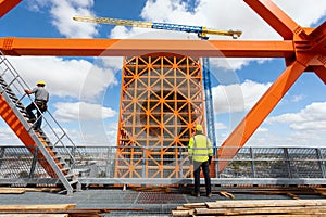 Construction workers on a high-rise building site with a crane and blue sky