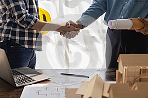 Construction workers holding helmets and vests are shaking hands. real estate