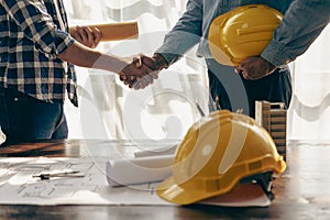 Construction workers holding helmets and vests are shaking hands. real estate