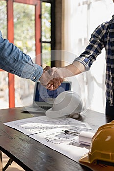 Construction workers holding helmets and vests are shaking hands. real estate