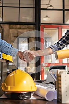 Construction workers holding helmets and vests are shaking hands. real estate