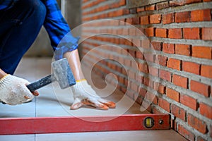 Construction workers or industrial tilers are working on ceramic tile floor tiles using rubber hammers to tap the floor to attach photo