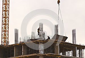 construction workers install metal rebar and build a new high-rise building against the backdrop of the sunset sky.