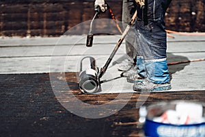 Construction workers installing bituminous membrane waterproofing system