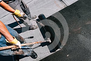 Construction workers installing bituminous membrane waterproofing system insulation with blowtorch photo