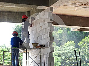 Construction workers installing lightweight block bricks to become wall at the construction site.