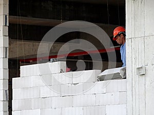 Construction workers installing lightweight block bricks to become wall at the construction site.