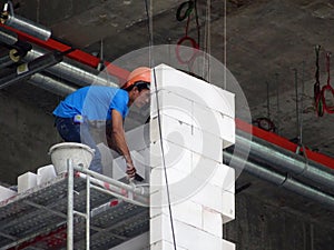 Construction workers installing lightweight block bricks to become wall at the construction site.