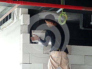 Construction workers installing lightweight block bricks to become wall at the construction site.