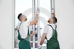 Construction workers installing plastic window