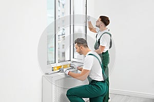 Construction workers installing plastic window