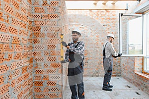 Construction workers installing window, checking brick wall level