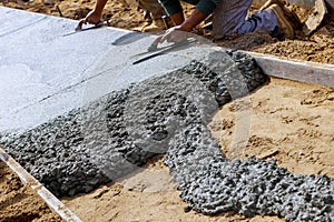 Construction workers laying concrete mixer with concrete mixer on sidewalk