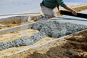 Construction workers laying concrete mixer with concrete mixer on sidewalk