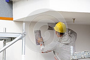 Construction workers plaster the facade of the house.