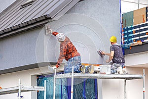 Construction workers plaster the facade of the house.
