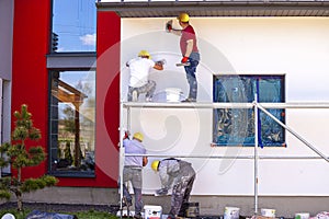Construction workers plaster the facade of the house.