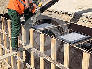 Construction workers are pooring concrete to formwork