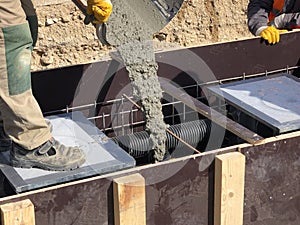 Construction workers are pooring concrete to formwork