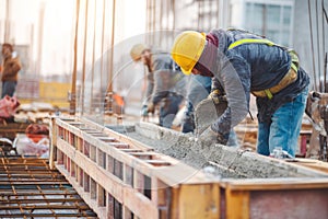 Construction Workers Pouring Concrete into Beam Formwork on Site