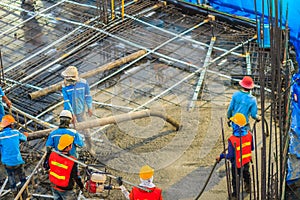 Construction workers are pouring concrete in post-tension flooring work. Mason workers carrying hose from concrete pump or also k