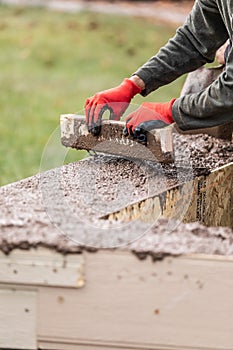 Construction Workers Pouring And Leveling Wet Cement Into Wood Framing