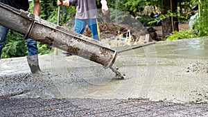 Construction workers pouring wet concrete for cement floors.