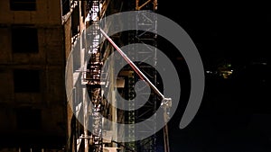 Construction workers pouring wet concrete using concrete spider hose or pump work at high-rise site in night