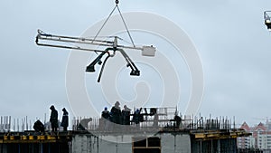 Construction workers pouring wet concrete using concrete spider hose or pump work at high-rise site. work in rain