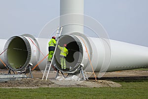 Construction workers preparing the rotor blades of a new wind turbine