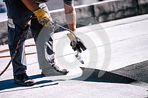 Construction workers, roofers installing rolls of bituminous waterproofing membrane for the waterproofing of new house. House