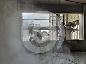 construction workers sanding a window that produces dust