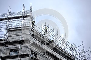 Construction workers on scaffolding high up on commercial building