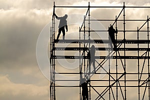 Construction workers silhouette working on iron platform sky background
