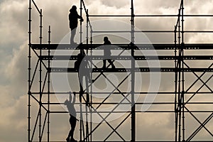 Construction workers silhouette working on iron platform sky background