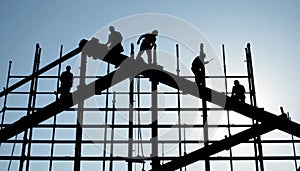 Construction Workers Silhouetted Against Sky on Steel Framework