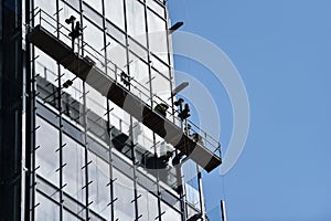 Construction workers on a suspended platform on a skyscraper photo