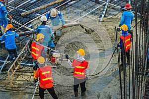 Construction workers using a concrete vibrator gasoline engine type at the construction site to compact the liquid concrete in r