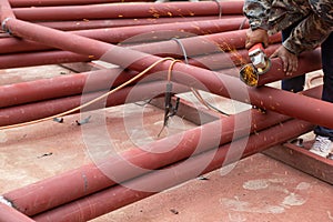 Construction workers are using grinding machines on large steel pipes. Used as a roof pole. Sparking while working Red painted