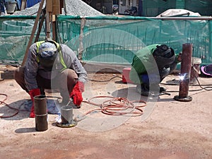 Construction workers welding pipes at the construction site.