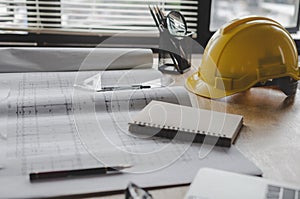Construction working tool, blueprint and yellow safety helmet on architect workplace desk