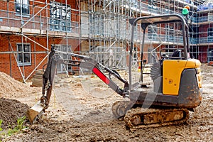 Construction works in progress on new residential building site and mini digger in front of it