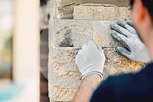 Constructionworker installing stone wall surface with cement for house renovating