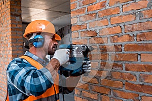 Constructor in helmet holding hammer drill