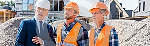 Constructors in helmets standing near businessman