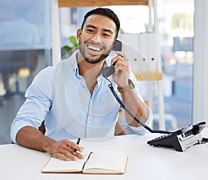 Consultant, businessman writing in a notebook and on a phone at his desk at work. Customer support or service, contact