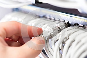 IT consultant connects a network cable into switch in datacenter